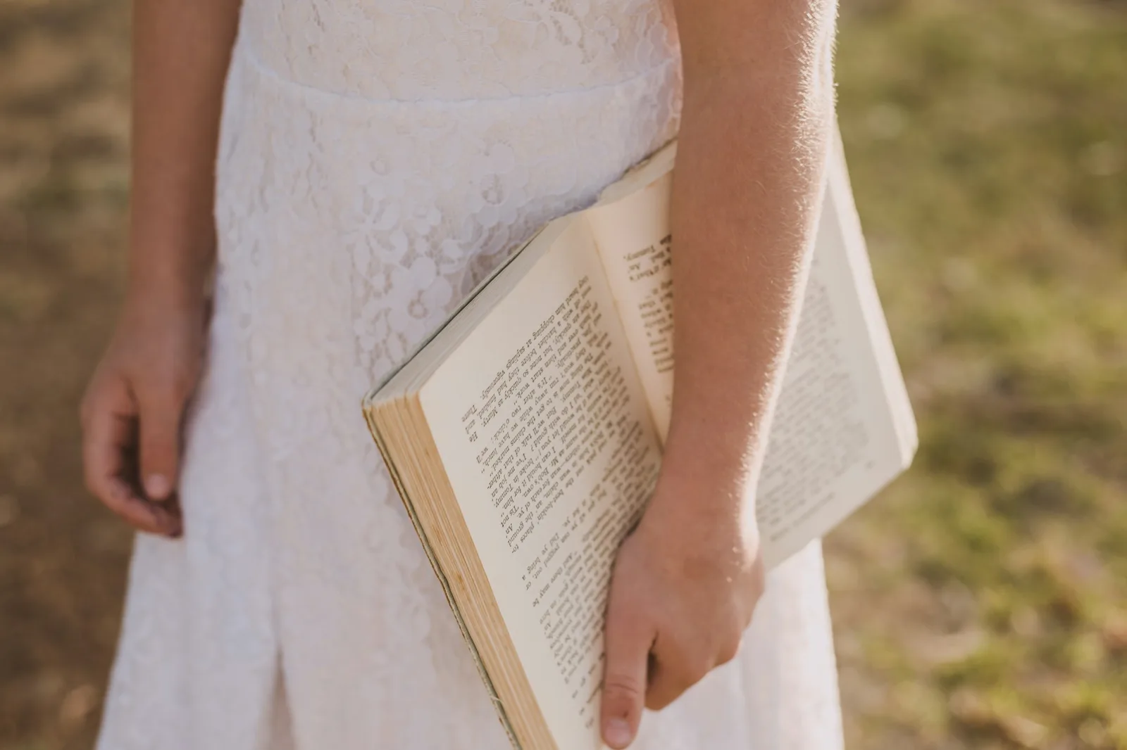 Close-up of a person holding an open book, focused on the printed text and reading posture