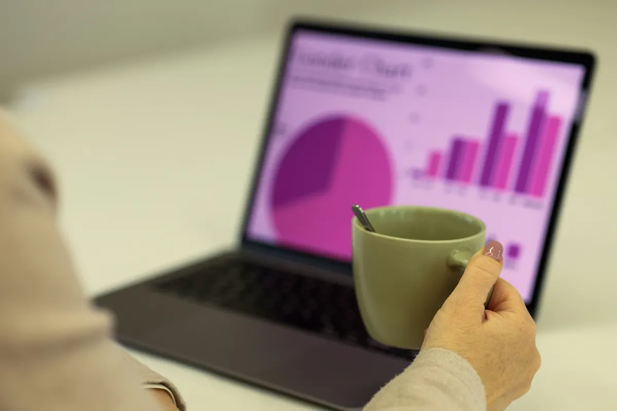 Person reviewing a dashboard interface on a laptop screen in an office environment