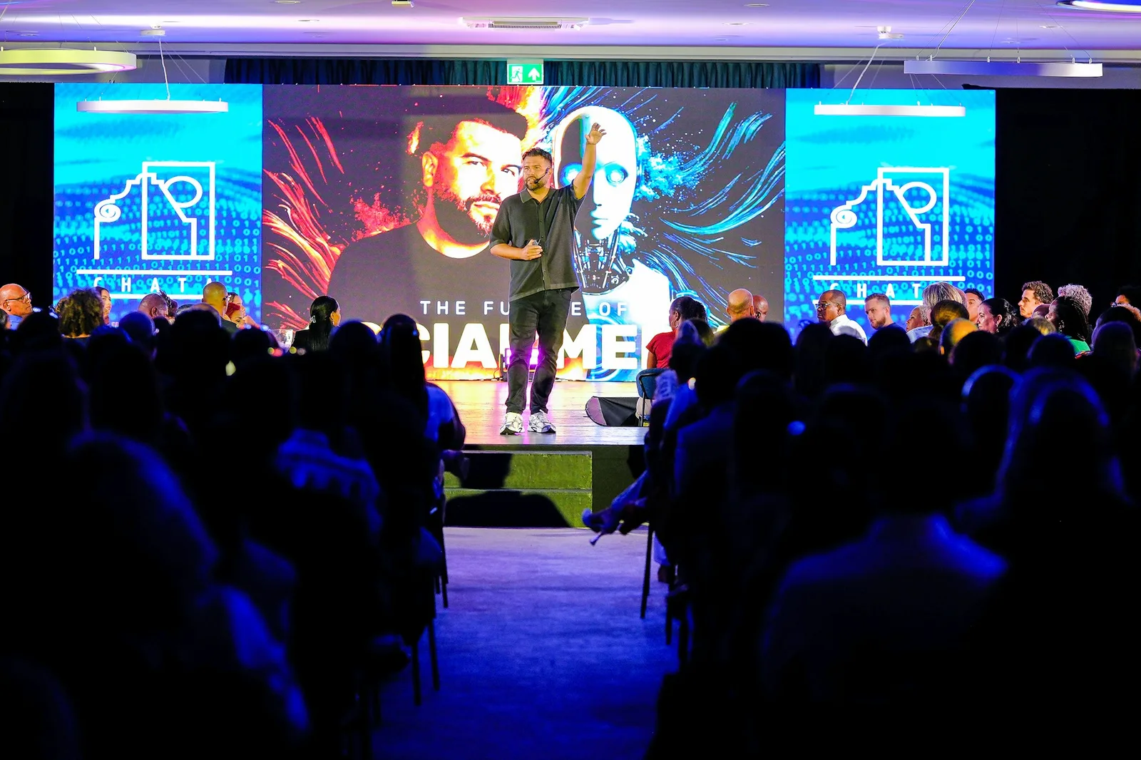 Speaker presenting on a conference stage to a seated audience