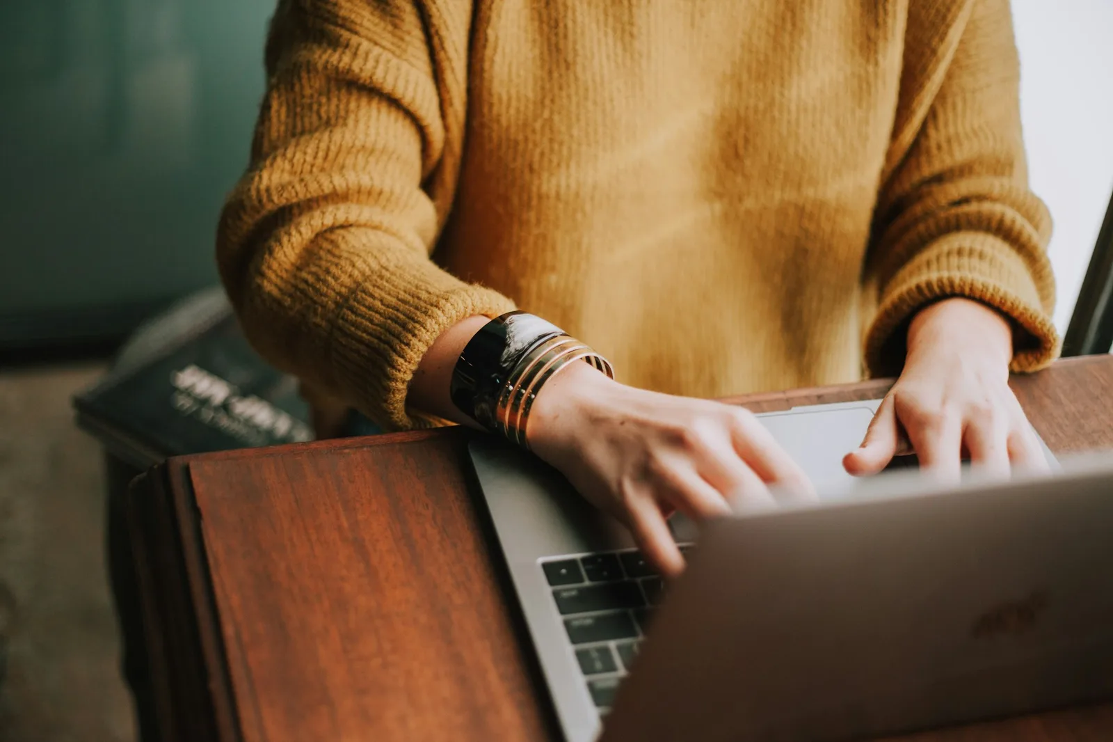 Person working on a laptop at a wooden table in a focused workspace