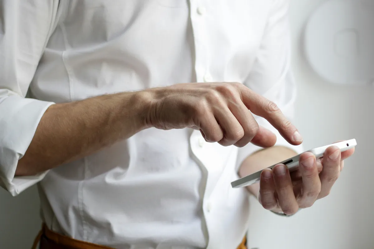 Close-up of a hand tapping a smartphone screen showing a button mid-animation
