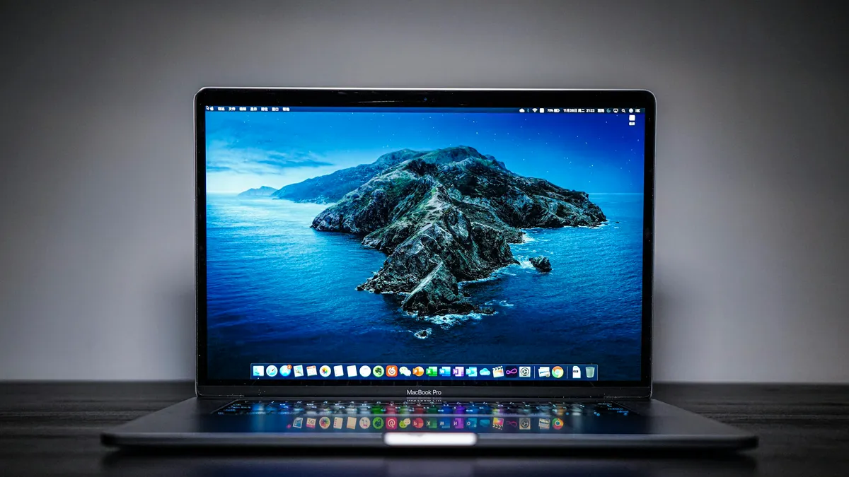 A black and grey laptop open on a desk with a dark screen