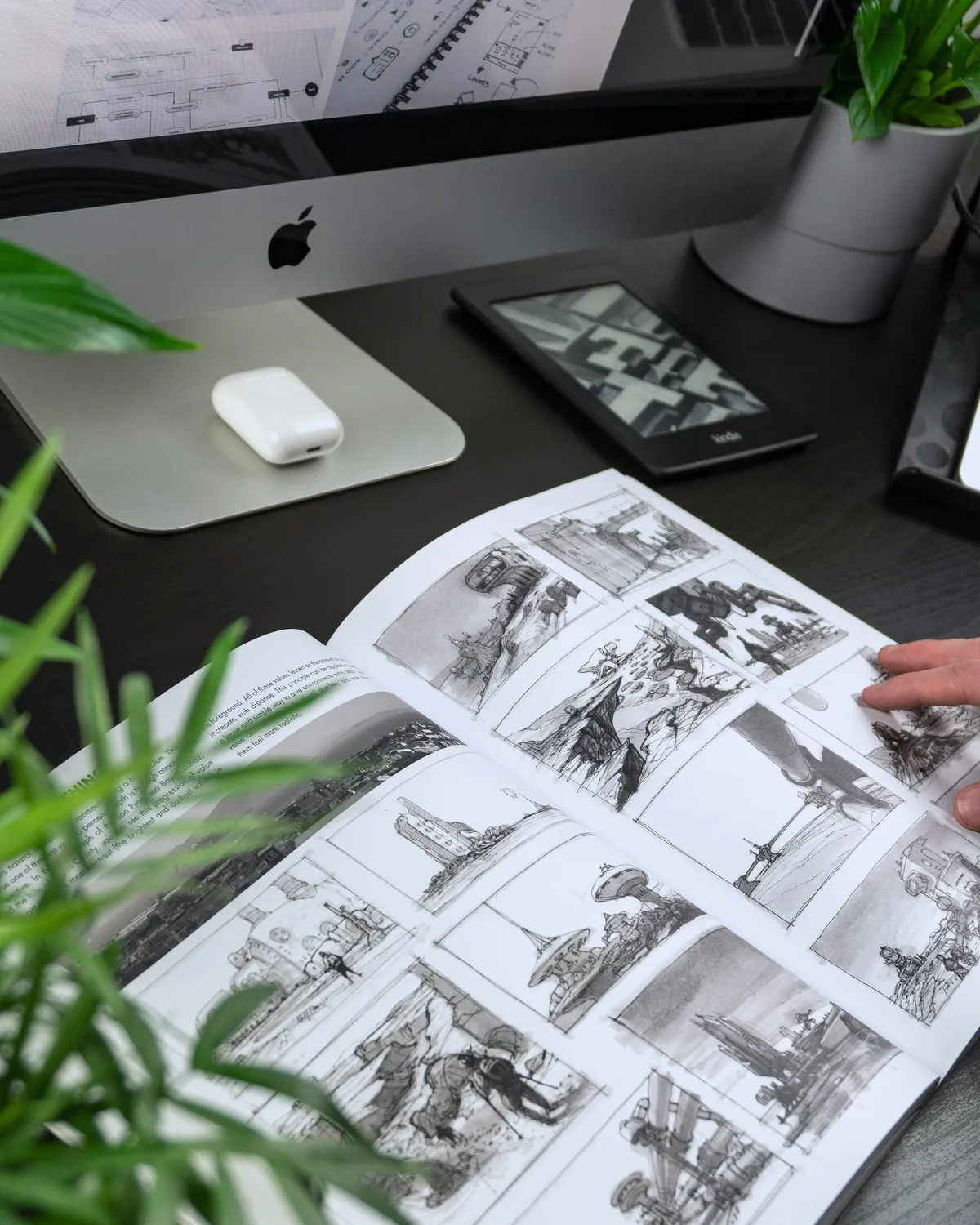 Motion designer reviewing a style frame layout printed on paper next to a laptop
