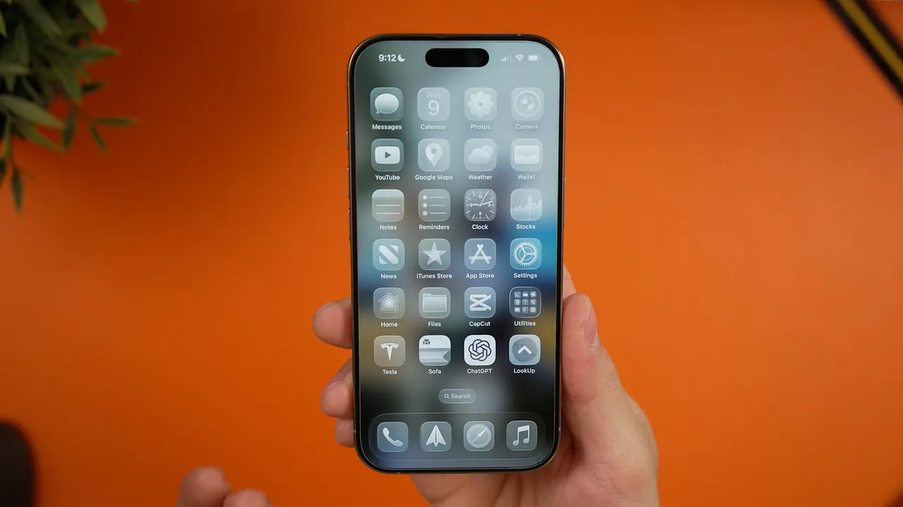 Hand holding an iPhone with the iOS home screen app grid on display, the surface Apple Intelligence redesigned