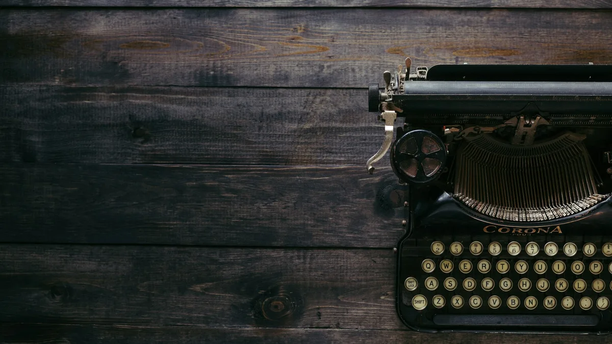Vintage black typewriter resting on brown wood planks, keys and typebars visible