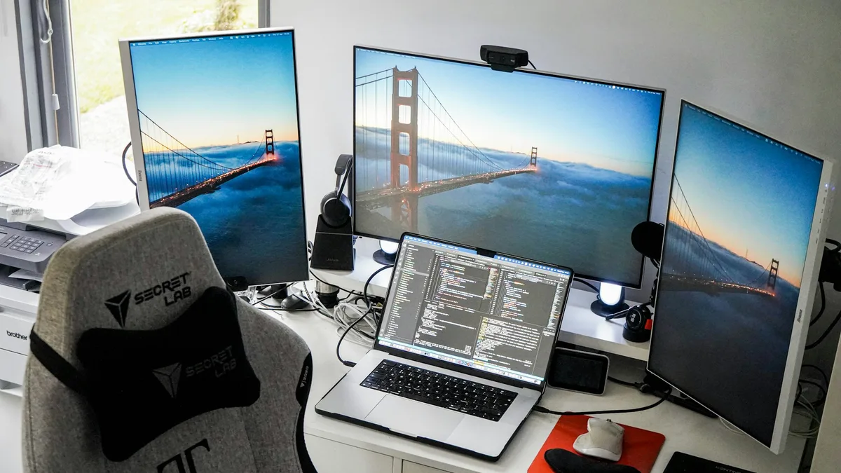 Desk setup with two monitors and a laptop displaying code and data