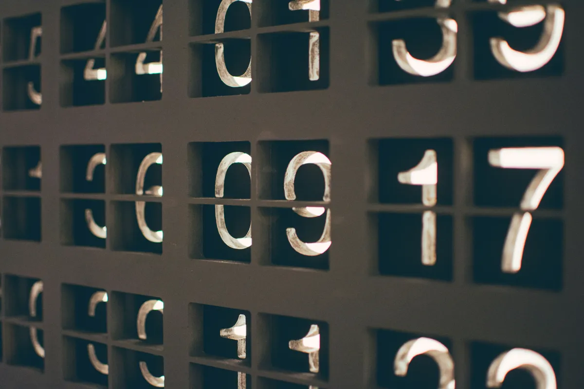 Close-up of backlit metal numerals set into a dark panel, like a mechanical counter mid-count