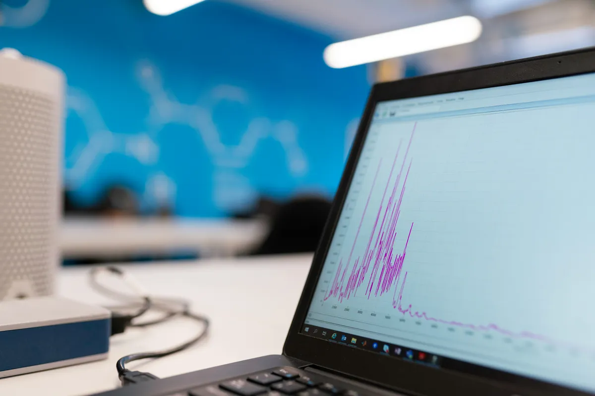 Laptop screen showing a spiky purple line chart on a bright office desk