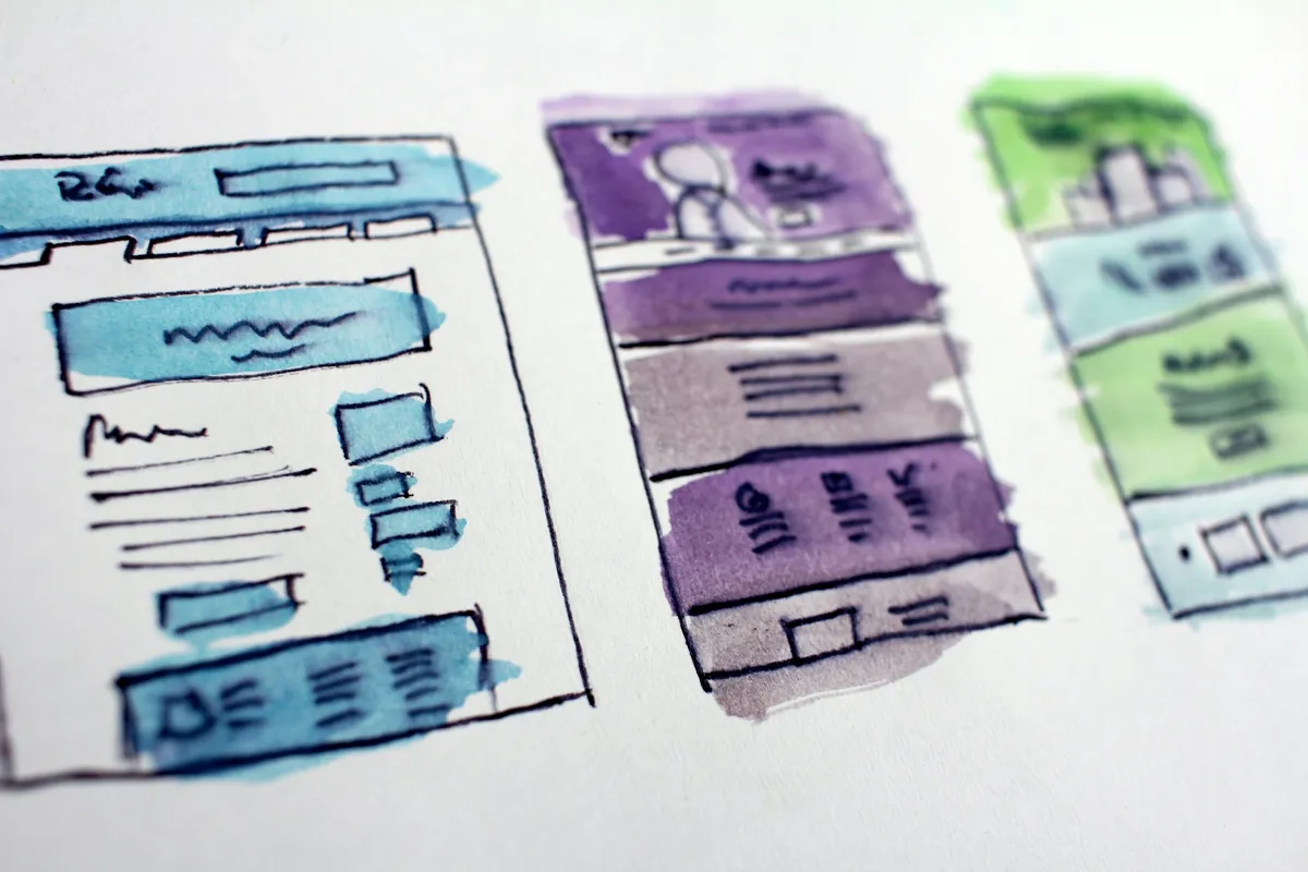 Hand-drawn wireframe sketches of website layouts spread across a desk