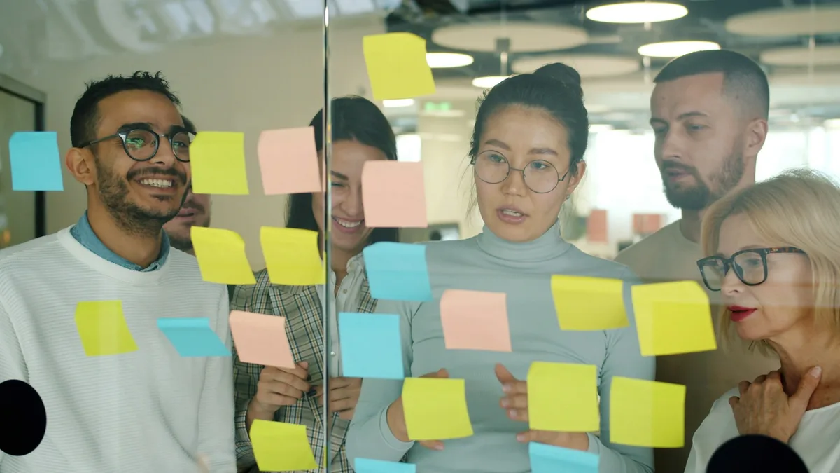 Team brainstorming with colorful sticky notes on a glass wall during a design workshop
