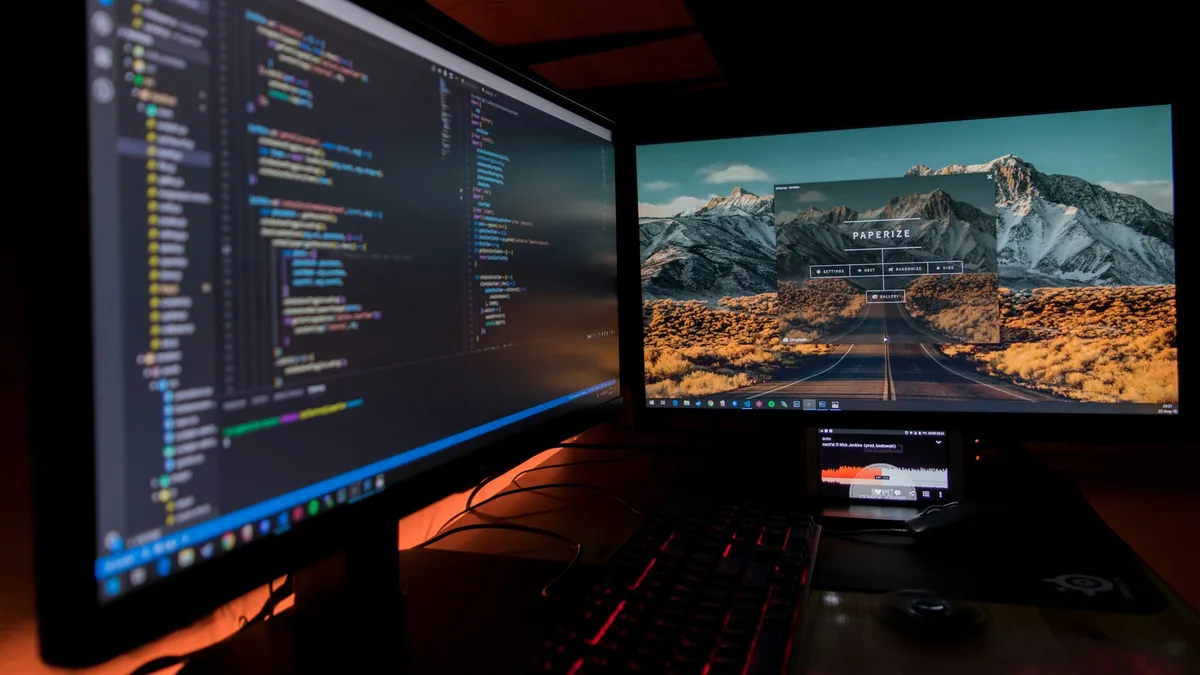 A dark code editor filling two monitors on a developer desk