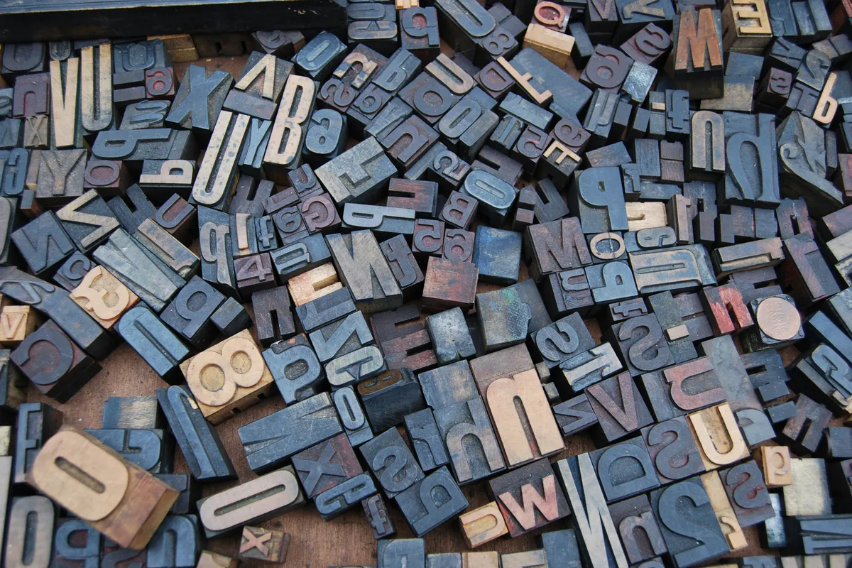 A tray of wooden letter stamps laid out in even rows and columns