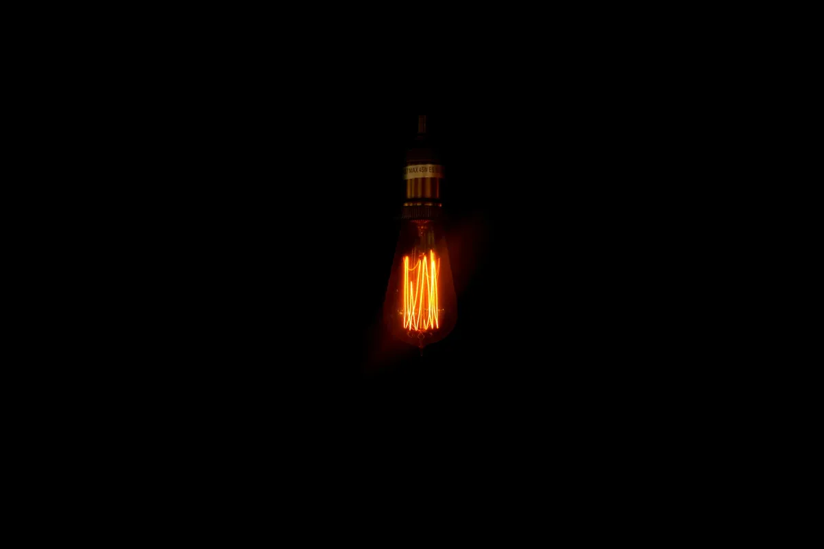 A single warm filament bulb burning against a black background