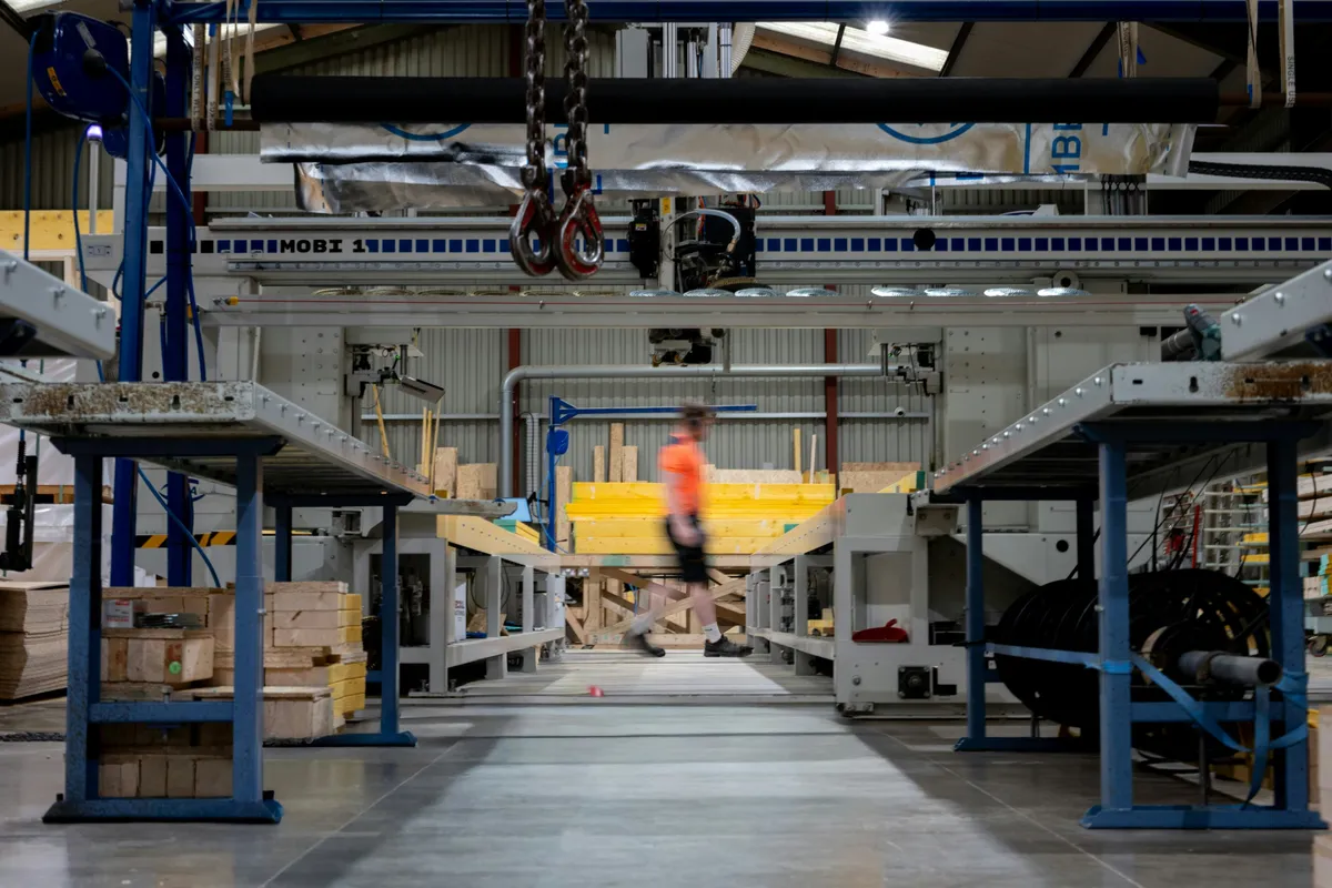 A worker walking a factory floor lined with machinery