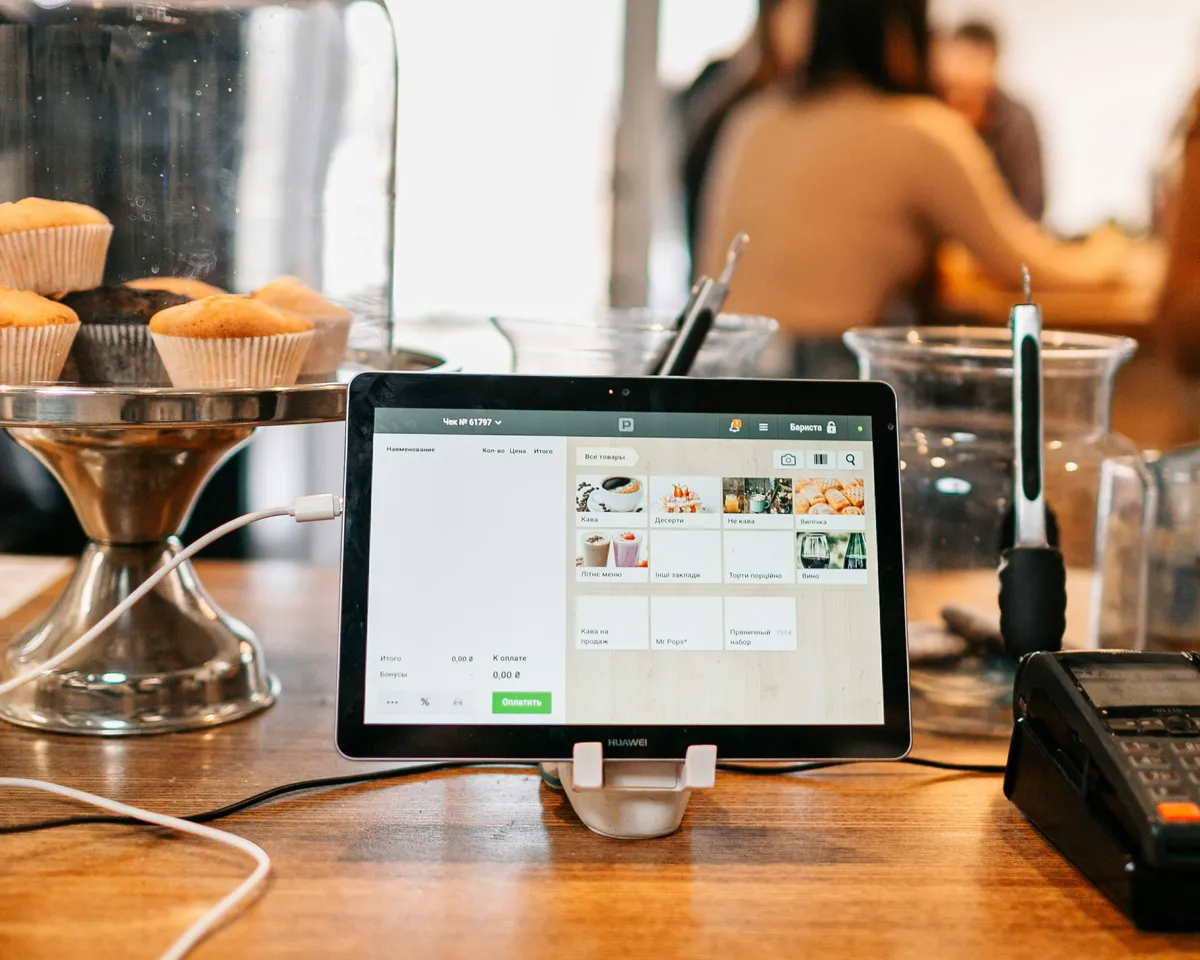Tablet POS system on a stand at a bakery checkout counter showing a product grid