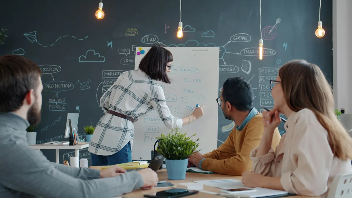 Team members collaborating around a whiteboard during an office discussion