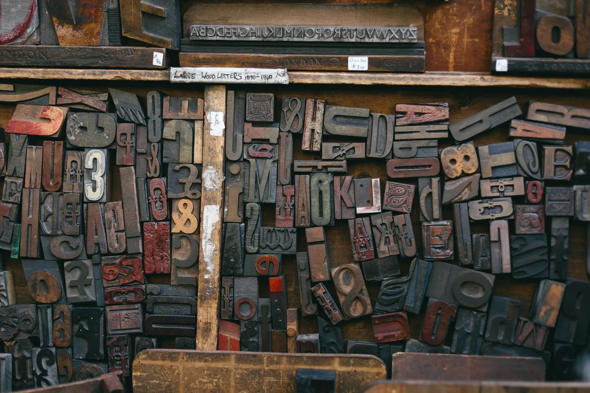 Assorted wooden type stamps scattered loose across a dark table
