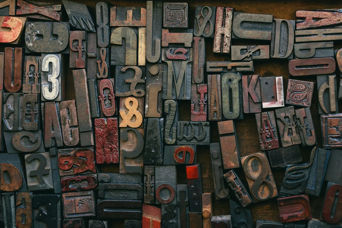 Wooden type blocks arranged into a deliberate cross on a dark surface