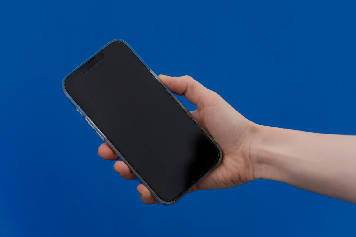 A phone held in one hand with the screen lit blue