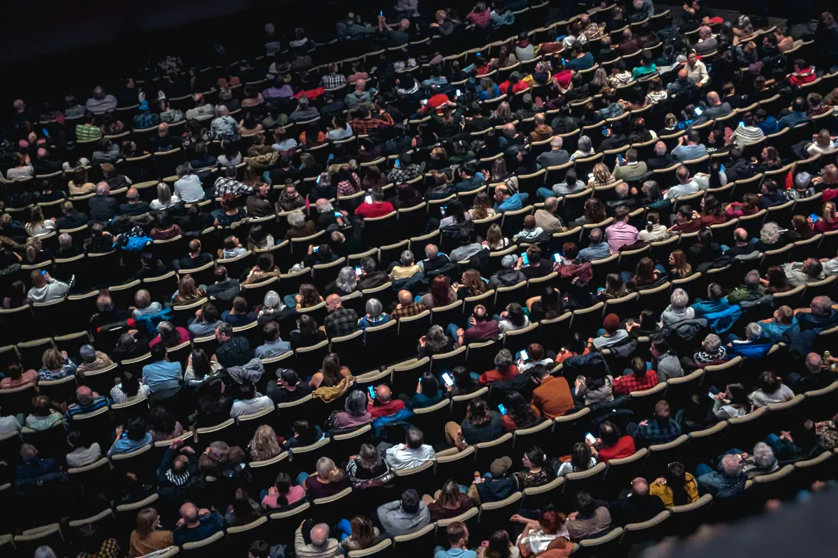 A large group of people seated in a darkened theatre