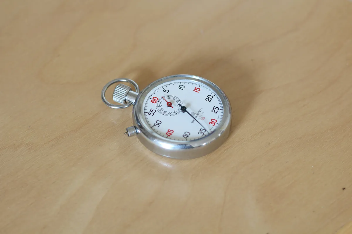A silver analog stopwatch with the second hand sweeping