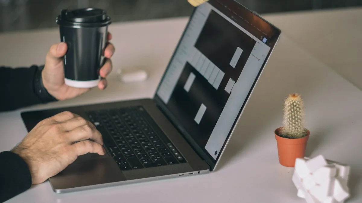 One hand holding a coffee cup while the other works on a MacBook showing a design prototype