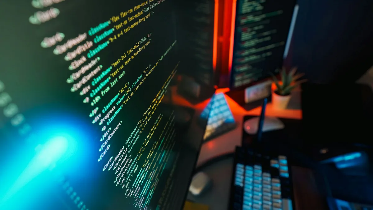 Code displayed across multiple computer screens in a dim office