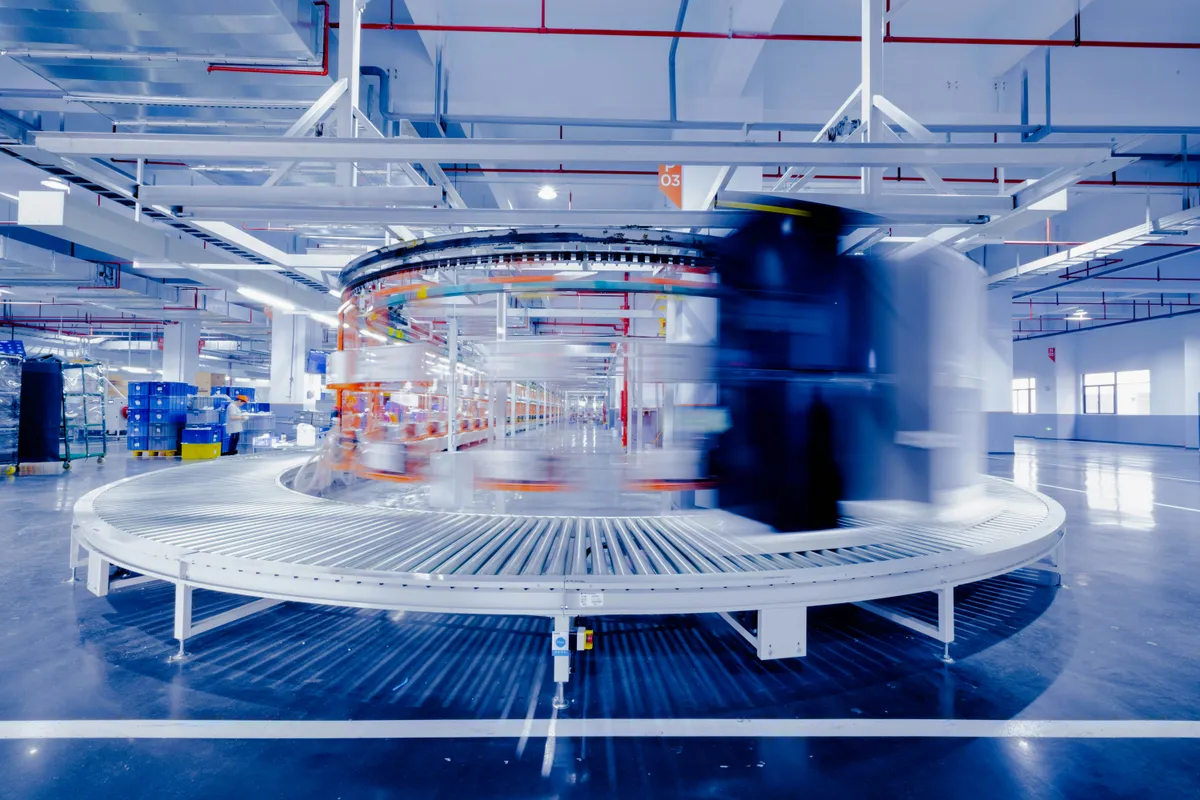A long exposure of an assembly line, the moving parts smeared into one arc