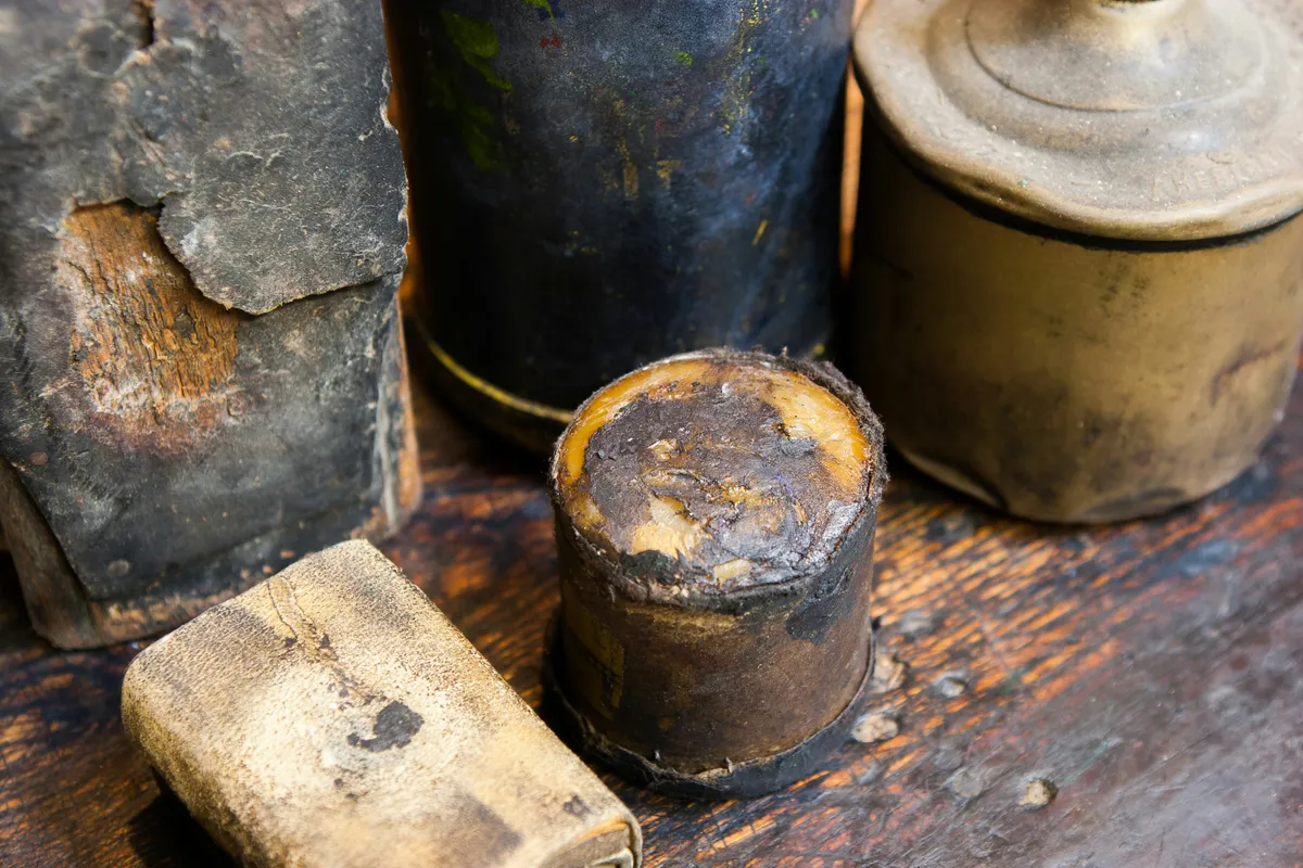 Two old ink canisters standing on a printers bench