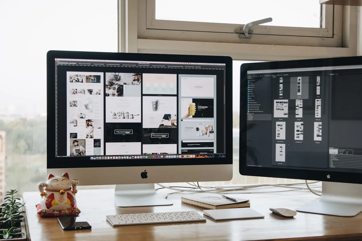 Two monitors on a desk showing colorful design software windows in a workspace