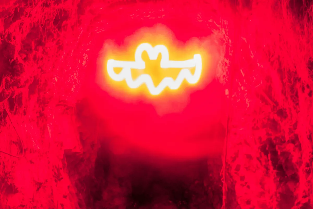 A single glowing yellow symbol burning against a deep red ground