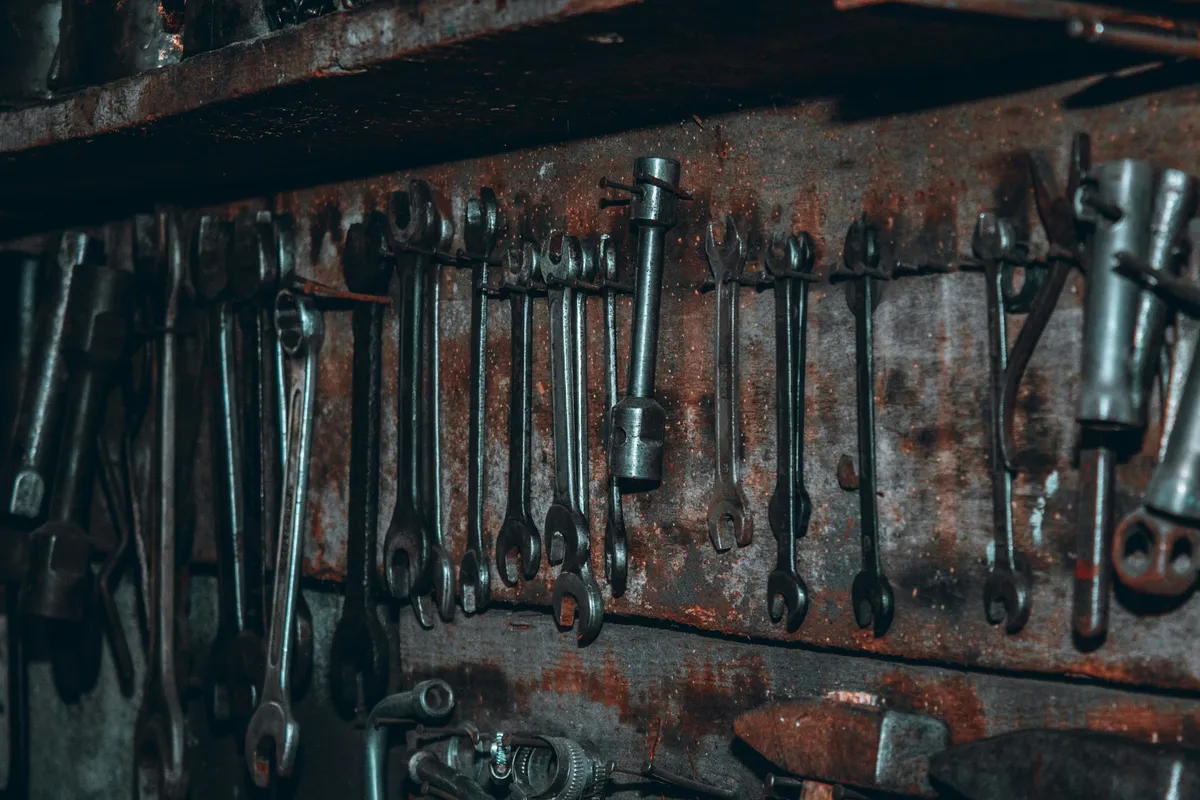 A row of black metal tools lined up along a shelf