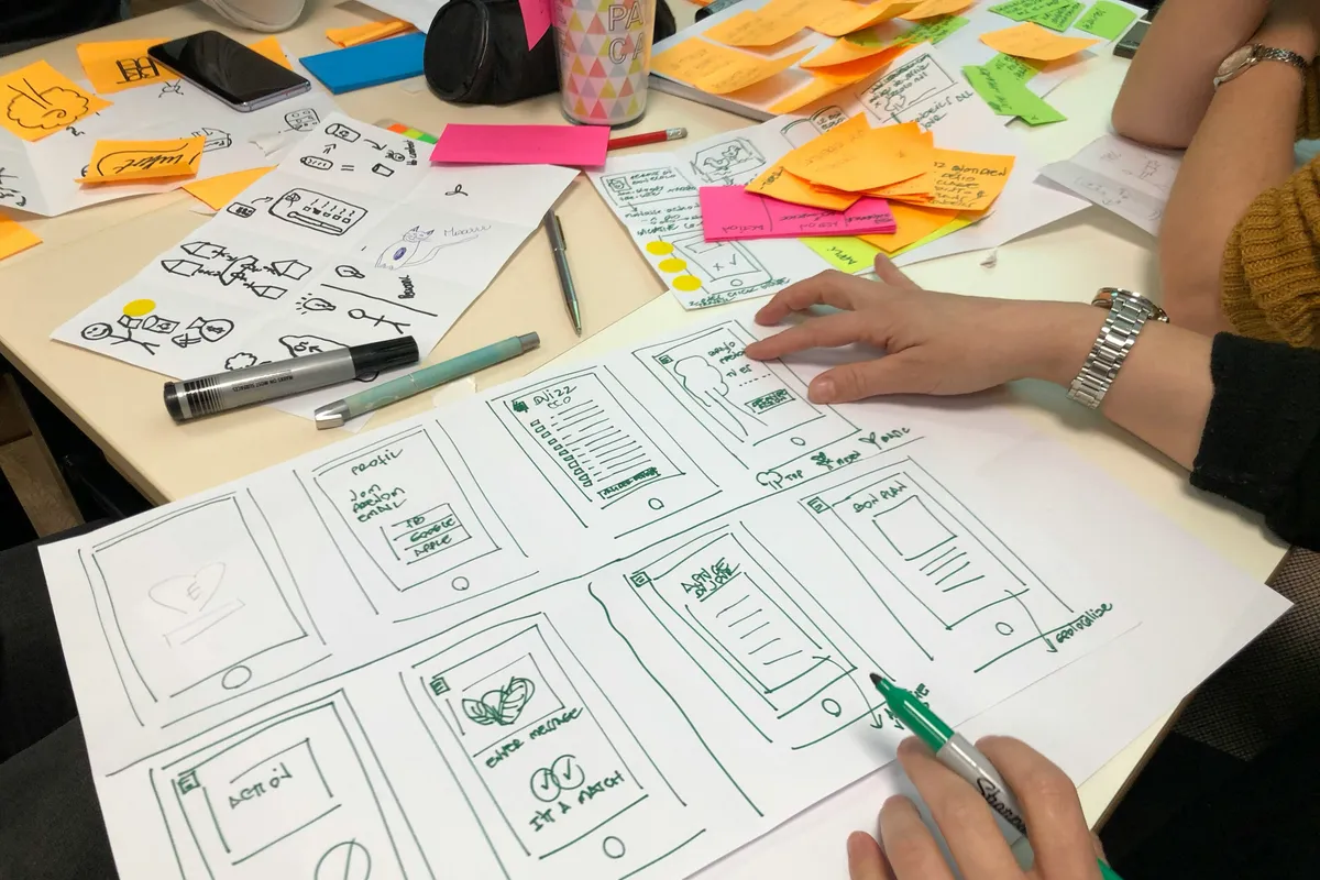 Hands drawing storyboard frames in pen on printed sheets during a planning session