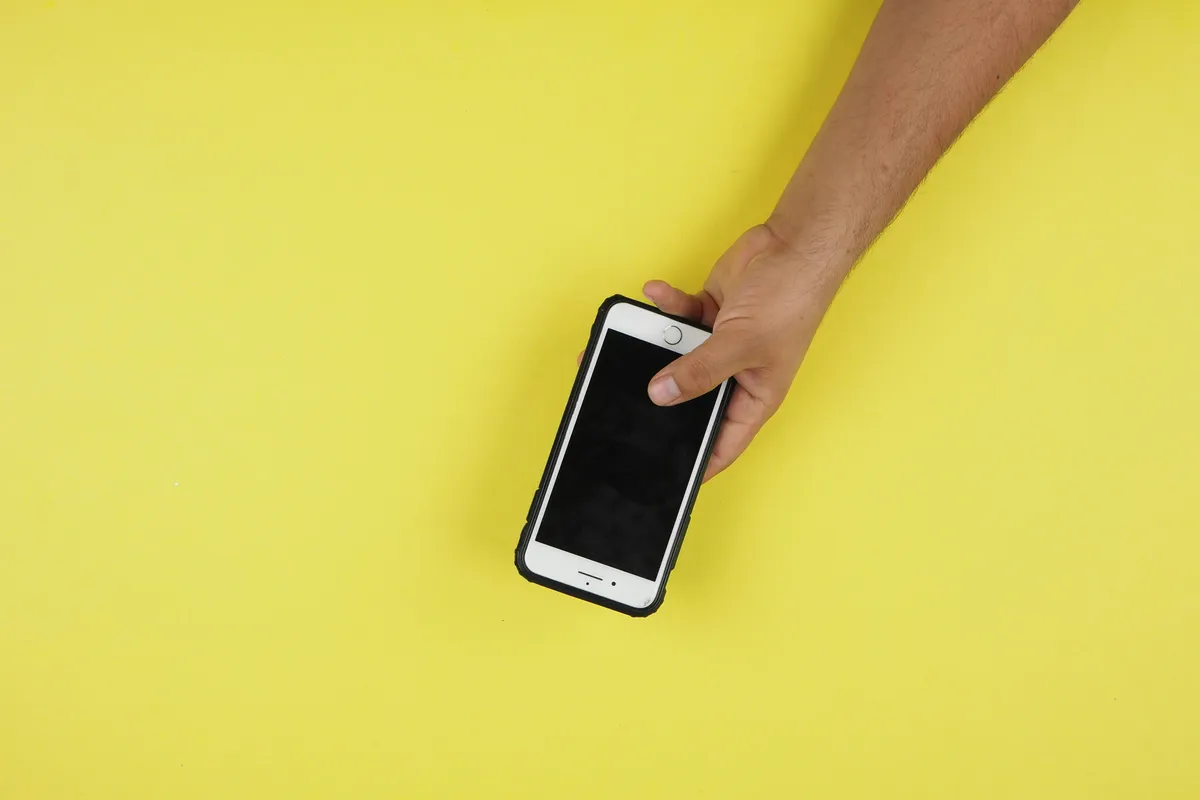 A silver phone lying flat with its screen the only bright thing in frame