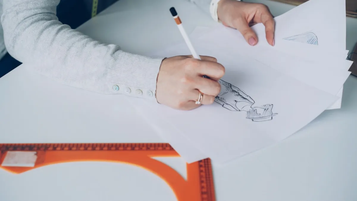 Designer hand sketching a wireframe layout on paper during the concept phase