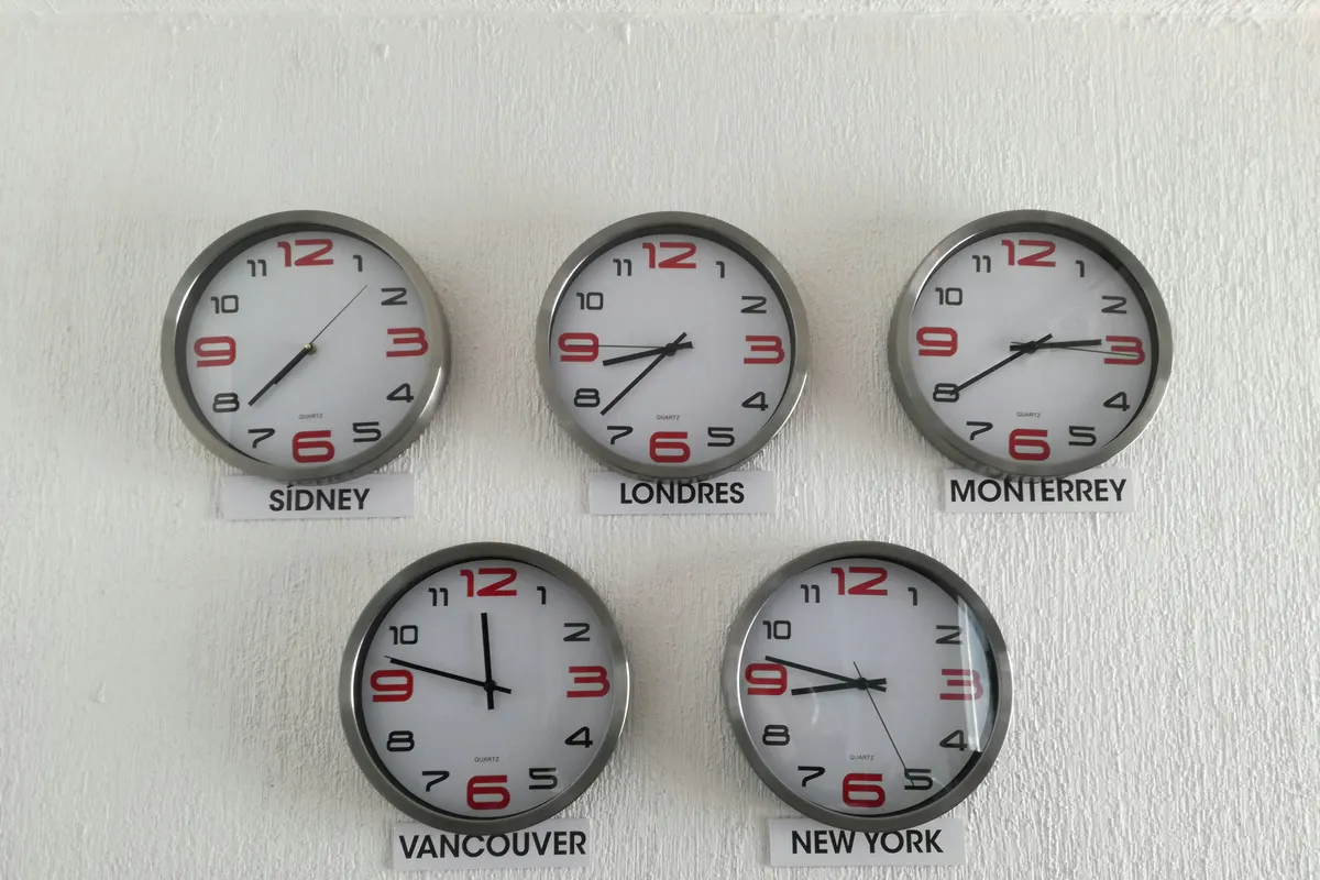 Five wall clocks labelled with city names showing different times side by side