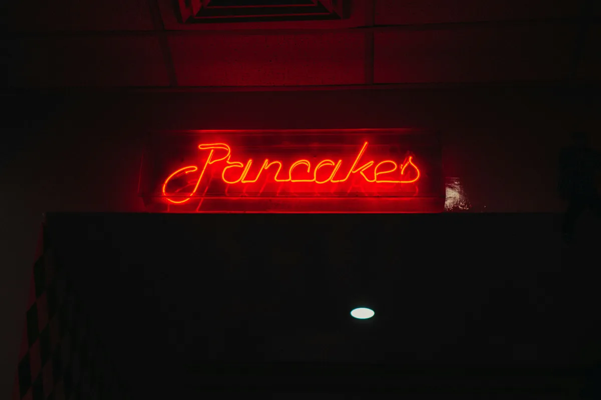 Red neon lettering with its glow bleeding into the dark around it