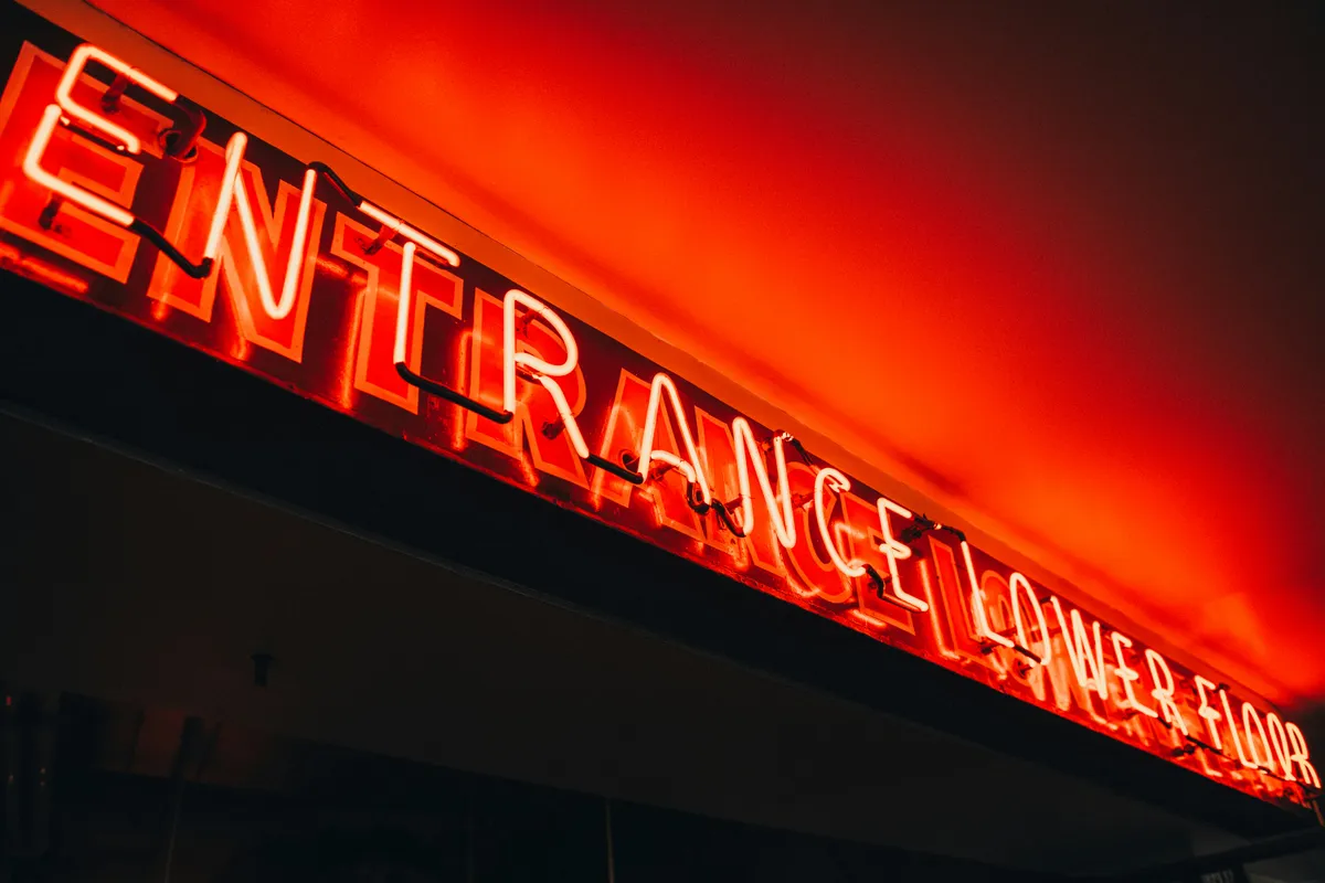 A bright red neon entrance sign hung against a dark ceiling