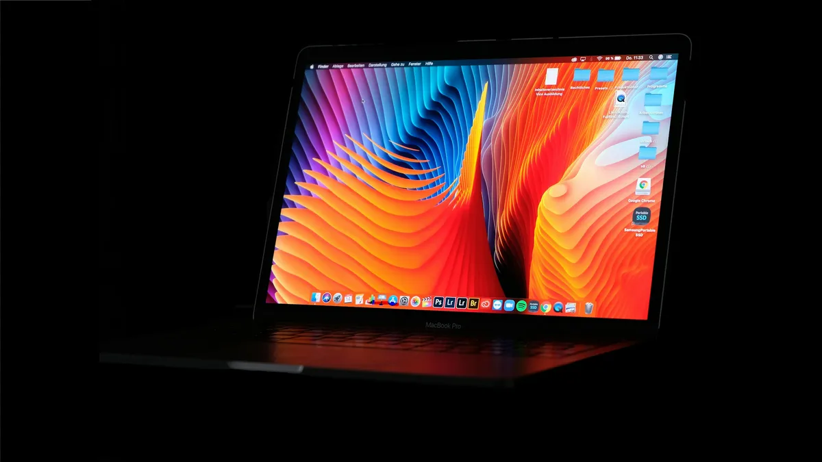 A black flat-screen monitor glowing on a desk in a dark room
