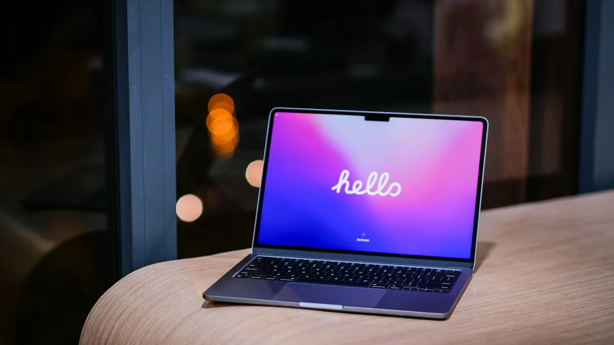 A laptop open on a wooden table showing a bright screen
