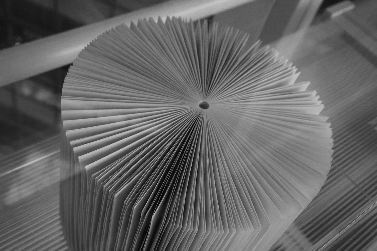 A grey fan of pleated paper folds radiating from a small hole in the center