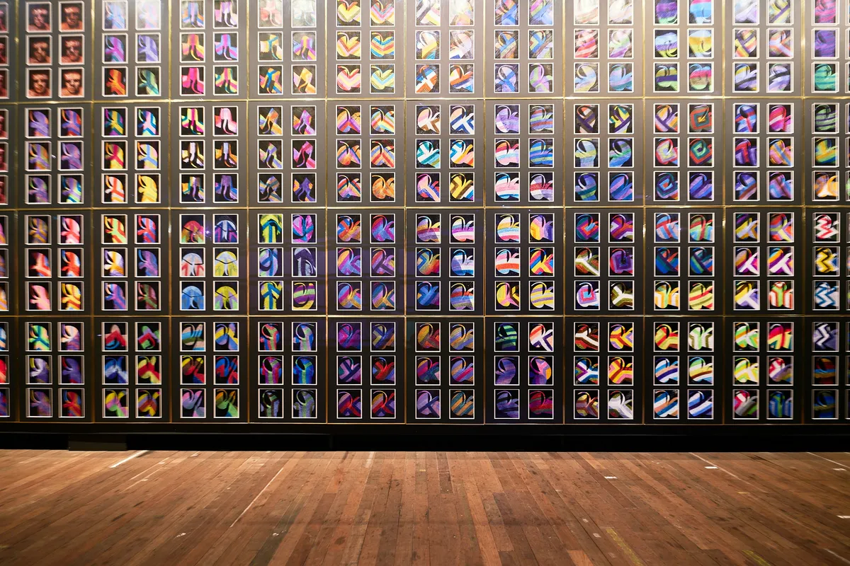 A wall of colourful framed works hung in even rows