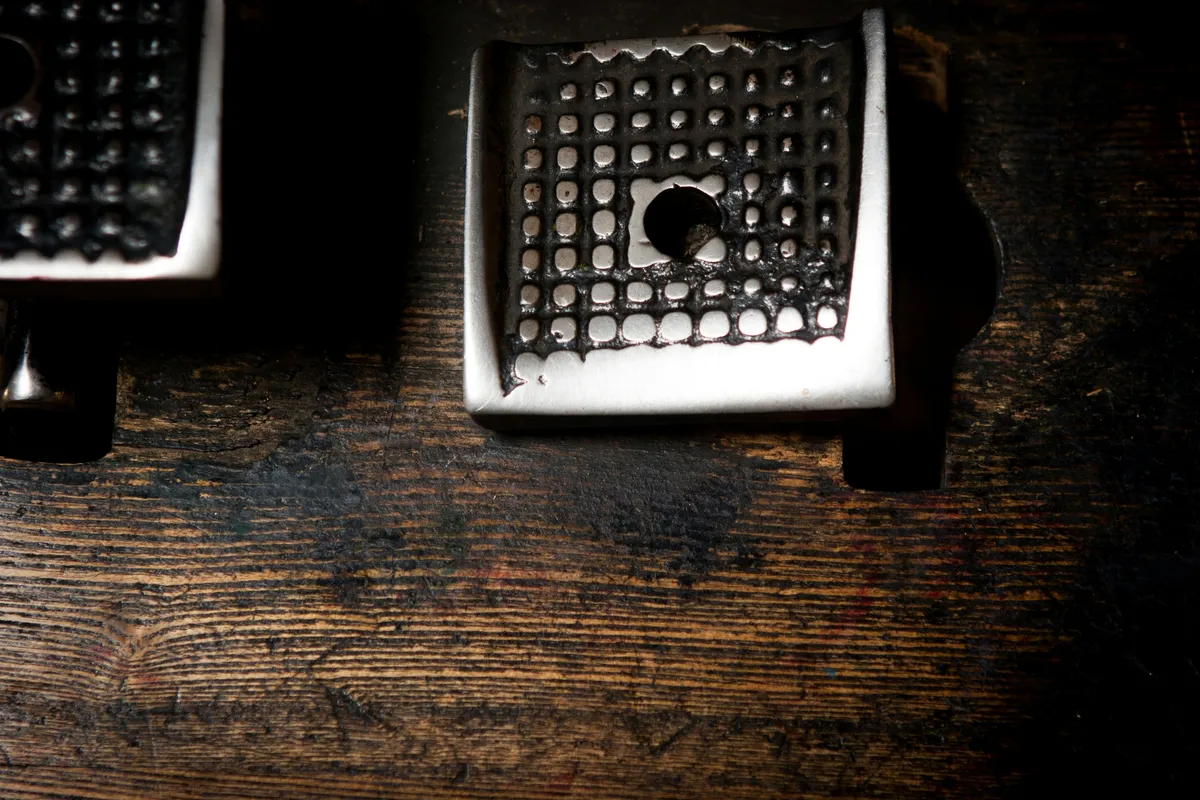 A metal type case on a wooden bench, every slot cut to its own size