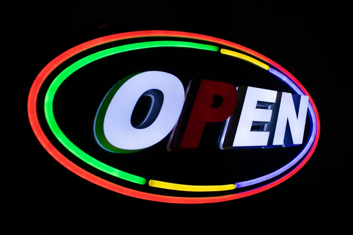 A thin neon tube spelling out one word, shot close in the dark