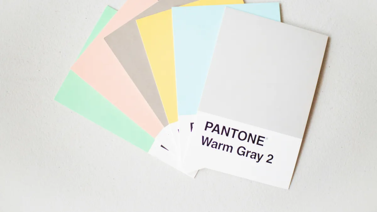 Fan of pastel Pantone swatch cards with Warm Gray 2 on top, near-identical light greys