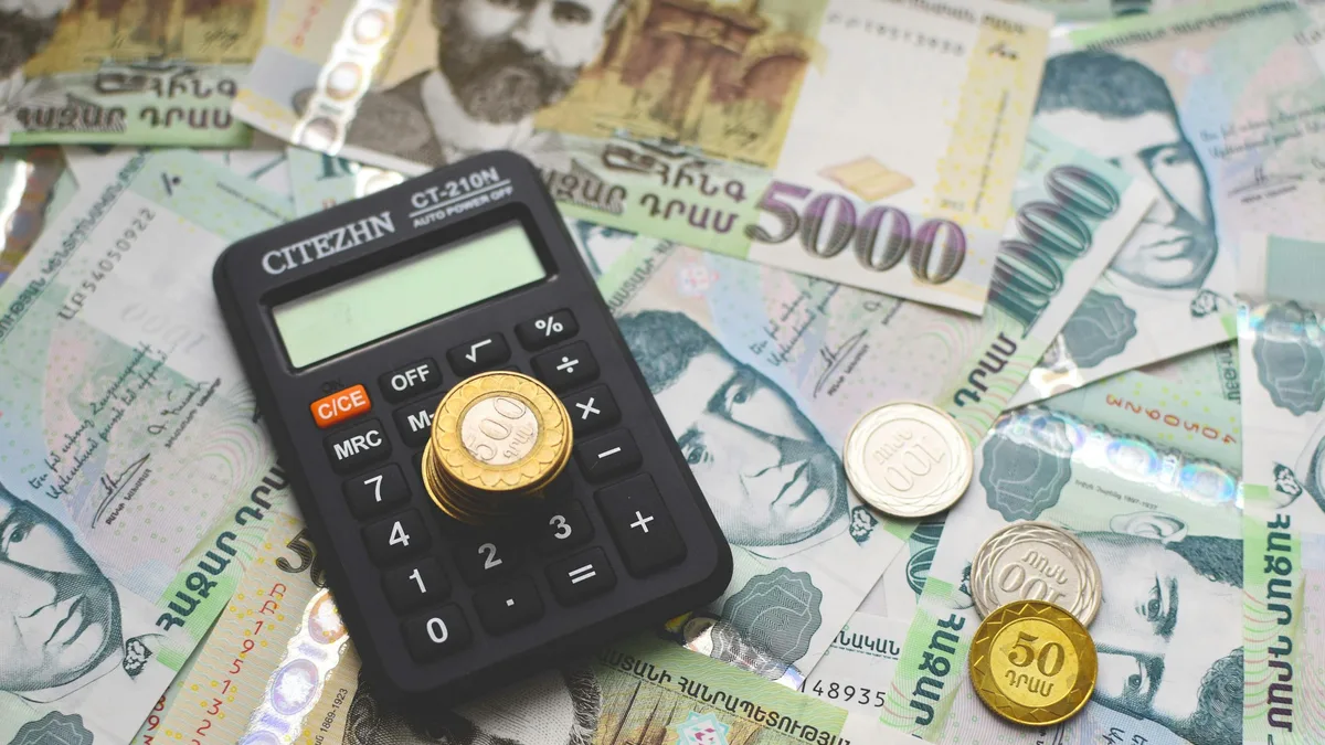 Armenian paper banknotes, coins, and a calculator arranged on a table