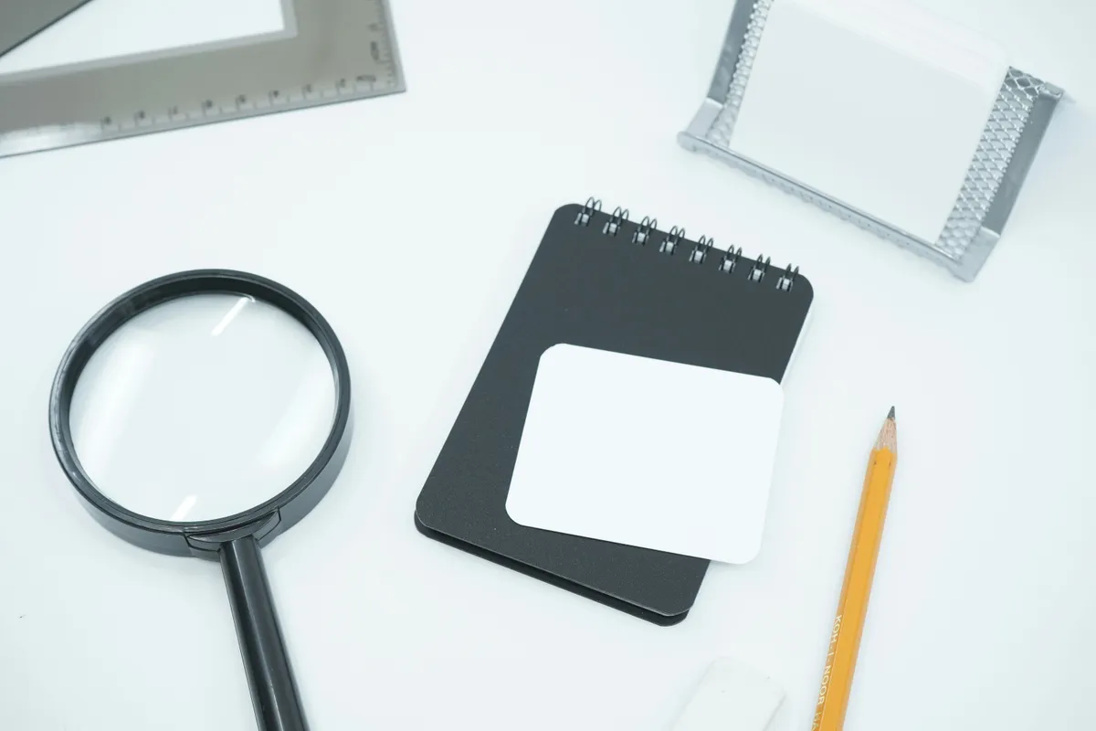 A black magnifying glass resting on a blank white page