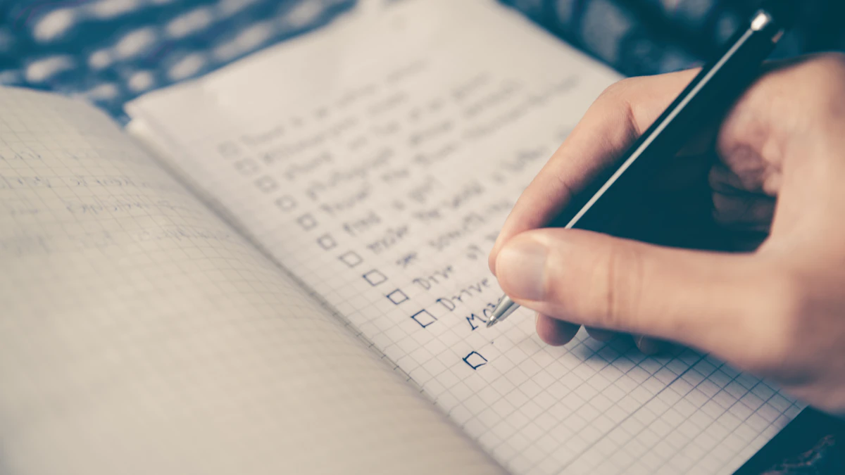 Hand writing a checklist in a notebook with a pen on a desk