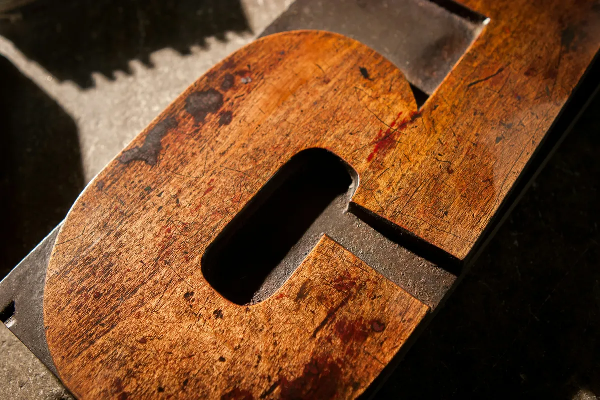 A close-up of a single worn wooden letterpress E