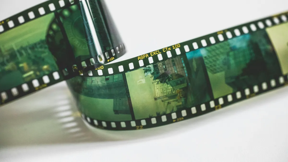 A 35mm film strip on a light table, its frames running left to right in sequence